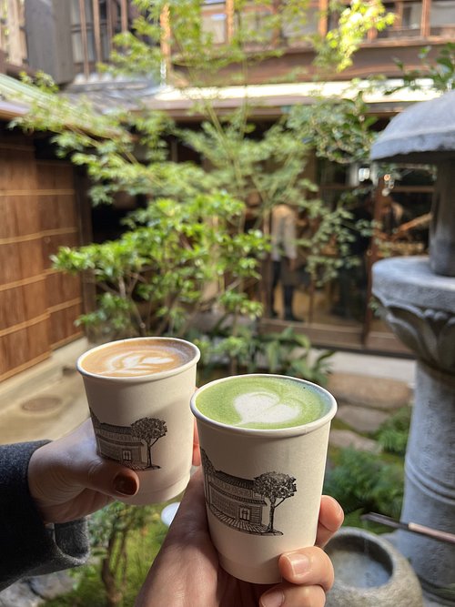 Two handcrafted lattes held in a garden courtyard